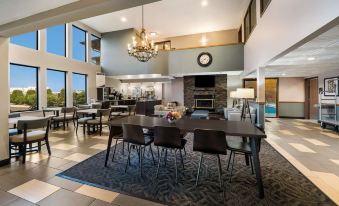 a spacious , well - lit dining area with multiple tables and chairs , a fireplace , and a view of the outdoors at Best Western Park Oasis Inn