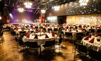 a large banquet hall with multiple round tables and chairs , all set for a formal event at Radisson Blu Caledonien Hotel, Kristiansand