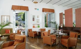 a modern living room with orange furniture , including chairs and couches , arranged around a coffee table at Hotel Vannucci