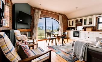 a cozy living room with a fireplace , dining table , chairs , and a kitchen area near the window at Lisnacurran