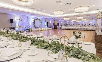 a well - decorated banquet hall with multiple tables set for a wedding reception , featuring white tablecloths and green centerpieces at Best Western Plus Pontoon Beach