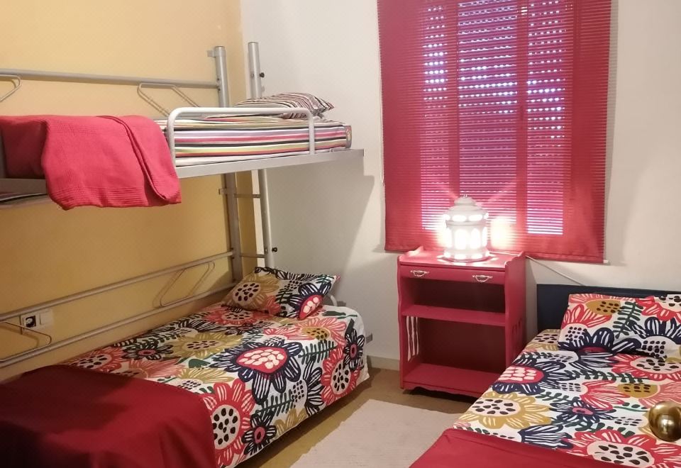 a small bedroom with three beds , one on top of the other , and a red curtain covering the window at The River Lee Hotel in Cork