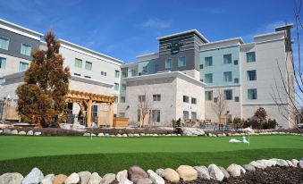 a large , modern hotel with a green lawn and a stone pathway in front of it at Homewood Suites by Hilton Hamilton