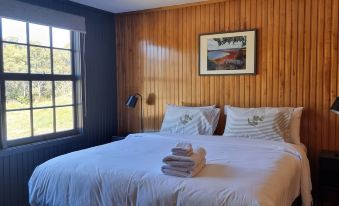 a large bed with white linens is situated in a room with wooden walls and a window at Great Lake Hotel