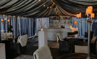 a bar area with a bar counter , several chairs , and a table under a tent at Best Western Plus Oaklands Hotel