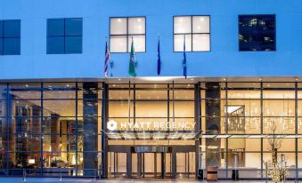 a modern building with a sign for hyatt regency , flags , and windows , set against a blue sky at Hyatt Regency Seattle