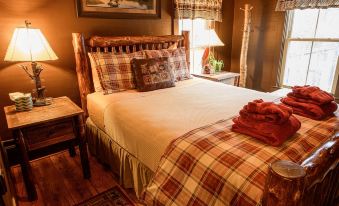 a cozy bedroom with a large bed , a window , and various items on the bed at RoosterComb Inn