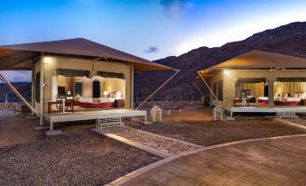 a luxurious resort with multiple tents , providing shade for guests while overlooking the mountains at dusk at Ras Al Jinz Turtle Reserve