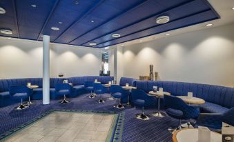 a modern restaurant with blue booths and tables , white walls , and blue carpet , giving it an inviting atmosphere at Hotel Norden