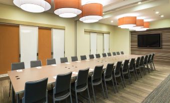 a long conference table with chairs and orange lamps is set up in a room at Even Hotel Rockville - Washington, DC Area, an IHG Hotel