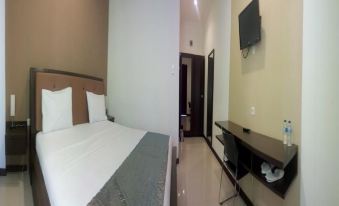 a hotel room with a bed , a desk , and a television mounted on the wall at Jazz Hotel Palu