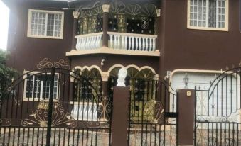 a brown two - story house with a white balcony and black fence , located in a residential area at Diamonds