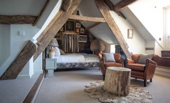 a cozy bedroom with wooden beams , a bed , and a wooden stool , all decorated in a rustic style at The Frogmill Hotel