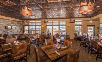 a large , well - lit dining room with wooden tables and chairs arranged for a group of people to enjoy a meal together at Grand Ely Lodge