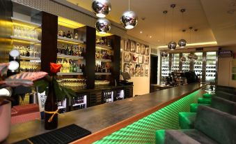 a modern bar with a long wooden bar counter , multiple wine glasses on the counter , and several bottles on display at Hotel Verde Cape Town Airport