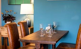 a dining table with four chairs surrounding it , along with wine glasses placed on the table at The Three Lions