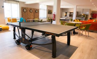 a ping pong table is set up in a room with chairs and tables around it at Hotel Acropolis