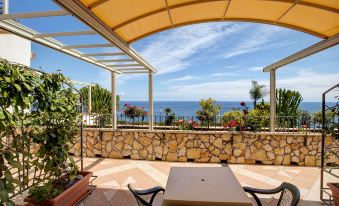 a beautiful outdoor terrace with a stone wall , stone wall chairs , and a view of the ocean at Hotel Antares