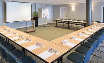 a conference room with a long table and chairs arranged in a semicircle , creating an open space at Ibis Luxembourg Sud