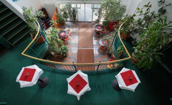 an aerial view of a hotel lobby with tables , chairs , and potted plants arranged throughout the space at Highway Hotel