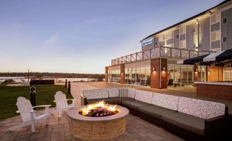 a fire pit with a fire burning in it on a patio overlooking a body of water at Wyndham Newport Hotel