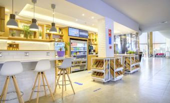 a modern , well - lit restaurant with a white bar counter and stools , along with various appliances and shelves at Hilton Garden Inn Malaga