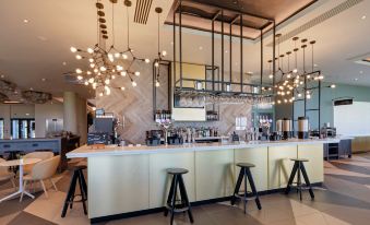 a modern coffee shop with a long bar counter , several stools , and a dining table at Hilton Garden Inn Doncaster Racecourse