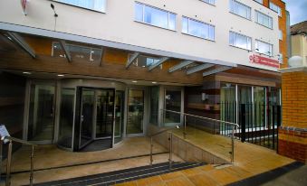 a building entrance with a metal railing , glass doors , and a wooden staircase leading up to it at Best Western Plus London Croydon Aparthotel