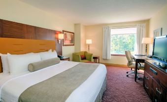 a large bed with white linens is in a hotel room next to a window at Sonesta Milwaukee West Wauwatosa