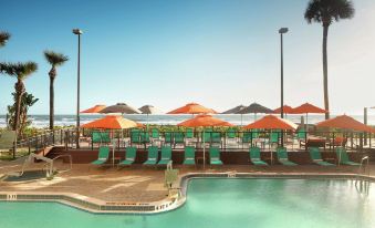 a resort with a large pool surrounded by lounge chairs and umbrellas , providing a relaxing atmosphere at DoubleTree Suites by Hilton Melbourne Beach Oceanfront
