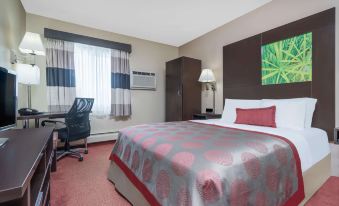 a hotel room with a red and white bed , a chair , a desk , and a window at Ramada by Wyndham Minneapolis Golden Valley