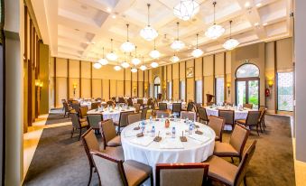 a large , elegant dining room with multiple round tables and chairs arranged for a formal event at Banyan Tree Tamouda Bay