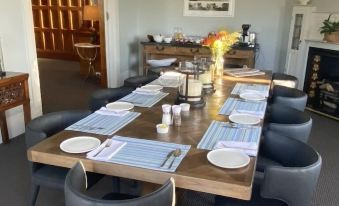 a dining room with a long wooden table set for a meal , surrounded by chairs at Cedar House