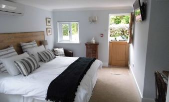 a cozy bedroom with a large bed , a television mounted on the wall , and a door leading to a garden at The Mill at Glynhir