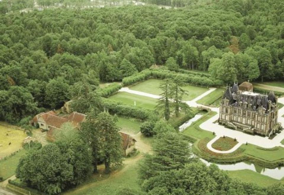 an aerial view of a large , lush green forest with a mansion in the distance at Center Parcs les Bois Francs