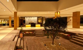 a modern , well - lit lobby with a tree in the center and stone steps leading to it at Hyatt Place Hampi