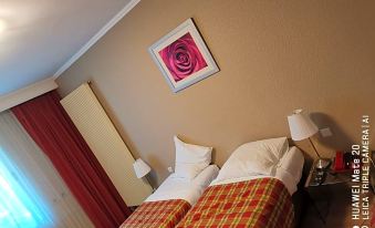 a cozy hotel room with two beds , white sheets , and a pink rose picture on the wall at La Cote d'Or