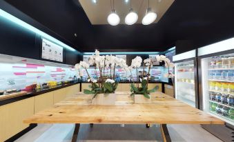 a large dining table with two vases of white orchids on it , surrounded by chairs and in a room with multiple lights at Aloft Coral Gables