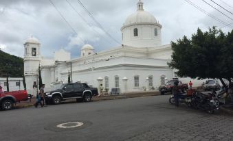 a white building with a dome and people walking on the street , cars parked in front of it at Hotel El Castillo
