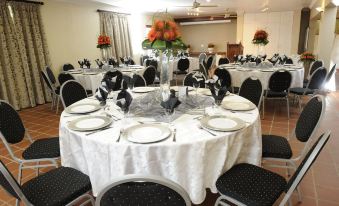 a large dining room set up for a formal event , with multiple round tables covered in white tablecloths and adorned with black and white at Oxford Lodge Vryheid