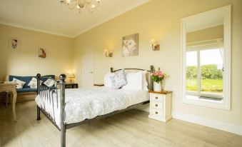 a spacious bedroom with a large bed , white walls , and a chandelier hanging from the ceiling at Hillcroft Accommodation