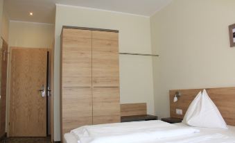 a hotel room with a wooden wardrobe and a bed , along with some white towels at Hotel Lindenhof