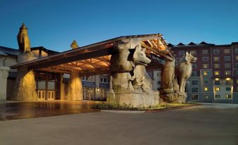 a large stone archway with a horse statue at the entrance of a building , illuminated by street lights at Great Wolf Lodge Grapevine