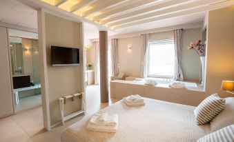 a large bed with white linens is in a room with a window and a television at Covo dei Saraceni