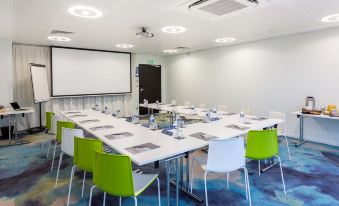 a conference room with a long table , chairs , and a projector screen , set up for a meeting or presentation at Campanile Laval Nord