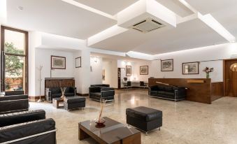 a spacious living room with a large flat - screen tv mounted on the wall , surrounded by couches and chairs at Hotel Minerva