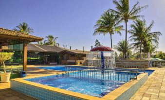 a large swimming pool with a water slide and palm trees in the background , under a clear blue sky at Brotas Eco Hotel Fazenda