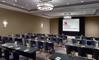 a large conference room with rows of chairs arranged in a semicircle , and a projector screen mounted on the wall at Atlanta Marriott Peachtree Corners