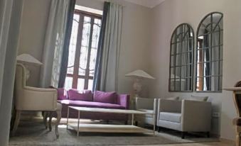 a modern living room with a purple couch , white armchairs , and a large window with arched windows at Hotel Villa Maria