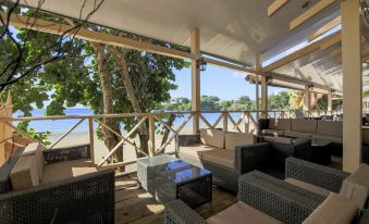 a large wooden deck overlooking a body of water , with several lounge chairs and a dining table set up for relaxation at Grafton Beach Resort